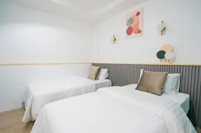 two beds in a room with white sheets at Phunaya Phuket Oldtown Hotel in Phuket Town