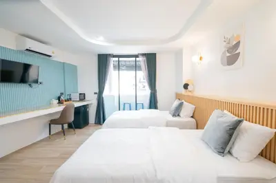 a hotel room with two beds and a desk at Phunaya Phuket Oldtown Hotel in Phuket Town