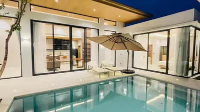 a swimming pool with an umbrella in a house at Mouana Residence Song Khun Chalong 8910 in Phuket Town