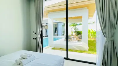 a bedroom with a bed and a large glass window at Mouana Residence Song Khun Chalong 8910 in Phuket Town