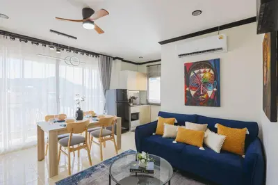 a living room with a blue couch and a table at Wink City 4 Patong Phuket in Patong Beach
