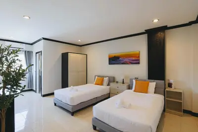 two beds in a hotel room with white and orange pillows at Wink City 4 Patong Phuket in Patong Beach