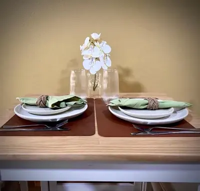 a table with two plates and a vase with white flowers at Casa Gris with Shared Pool in Ban Bo Han