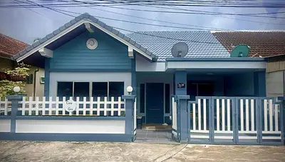 a blue house with a white fence in front of it at Casa Gris with Shared Pool in Ban Bo Han