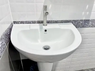 a white sink in a white tiled bathroom at Abir Homestay Koh Yao Yai in Ban Phlu Nai