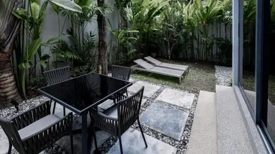 a patio with a black table and chairs and plants at Luxury Modern Loft Villa Riverhouse in Laguna Phuket