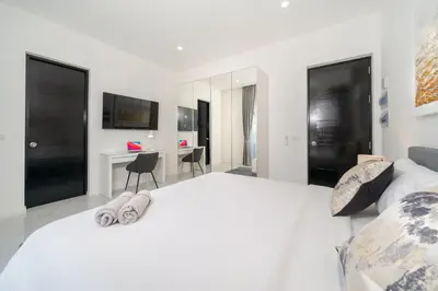 a bedroom with a large white bed and a desk at The Greens Phuket Villa with swimming pool 18 in Ban Saiyuan (1)