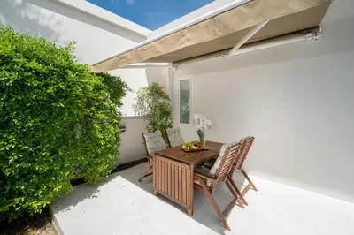 a table and chairs on a patio with a hedge at The Greens Phuket Villa with swimming pool 18 in Ban Saiyuan (1)