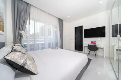 a white bedroom with a bed and a desk at Brand New 3 Bedroom Pool Villa 18 in Ban Saiyuan (1)