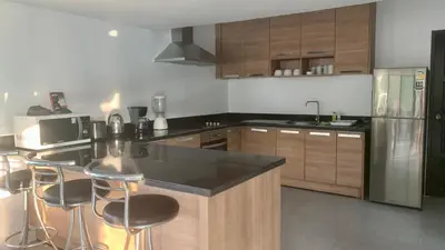 a kitchen with wooden cabinets and a black counter top at Villa Loma 4 Chambres in Patong Beach