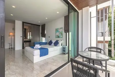 a bedroom with a bed and a table on a balcony at Vibrant Life at 4BR Pool Villa, Kata - UTK3 in Kata Beach