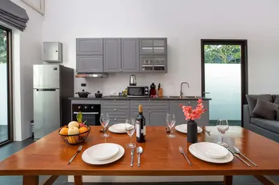 a kitchen with a wooden table with plates and wine glasses at Thai Balinese Villa Rico in Kamala 3BR, Private Pool in Kamala Beach