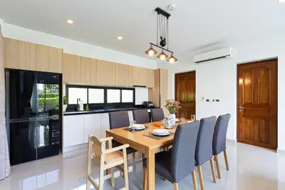 a kitchen and dining room with a wooden table and chairs at Phuket Nai Han Beach Villa with Pool in Rawai Beach