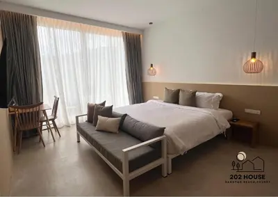 a bedroom with a bed and a couch in front of a window at 202 HOUSE near Bangtao Muay Thai & MMA in Ban Thalat Choeng Thale