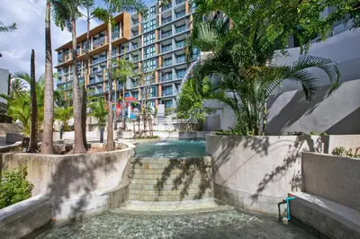 a swimming pool in front of a building with palm trees at 1bdr Seaview Apartment near Surin Beach in Surin Beach