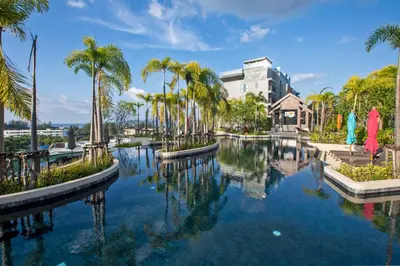 a pool of water with palm trees and a building at 1bdr Seaview Apartment near Surin Beach in Surin Beach