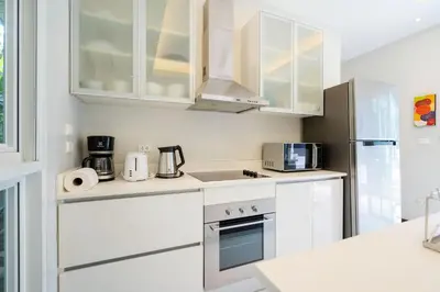 a white kitchen with white cabinets and appliances at Balinese Style 3BR Villa Morning Forest, Nai Harn in Rawai Beach