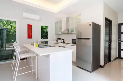 a white kitchen with a refrigerator and a sink at Balinese Style 3BR Villa Morning Forest, Nai Harn in Rawai Beach