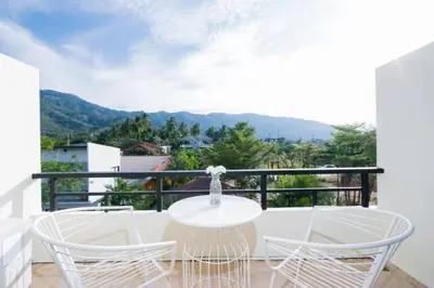 a white table and chairs on a balcony with mountains at Apartments Near Bangtao Muay Thai & MMA in Ban Thalat Choeng Thale