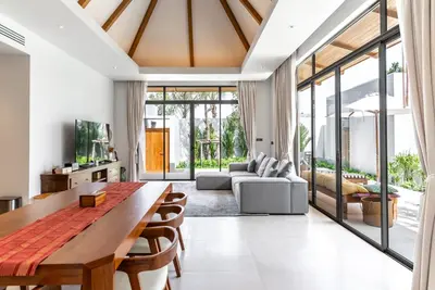 a living room with a wooden table and a couch at Anchan Flora by Villacarte in Ban Phru Champa