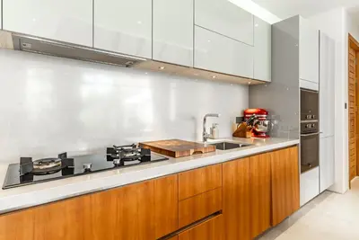a kitchen with wooden cabinets and a counter top at Anchan Flora by Villacarte in Ban Phru Champa