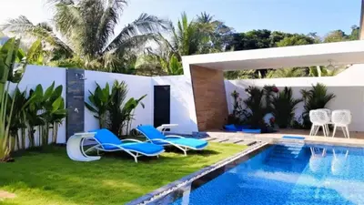a backyard with a swimming pool and chairs next to a house at 01 - Beach Villa Retreat in Nai Yang Beach