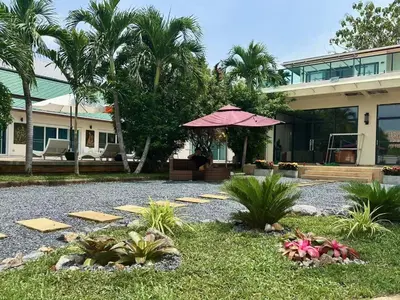 a house with an umbrella in front of a yard at Chuan Pool Villa Rawai Phuket in Rawai Beach