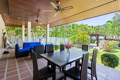 a dining table and chairs on a patio with a ceiling fan at 3BR Villa Barnabé with Lush Garden in Rawai Beach