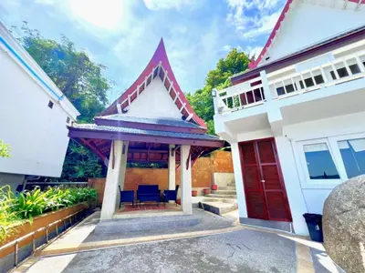 a house with a red door and blue chairs at Jaokhun Bayview Kamala, Phuket in Kamala Beach