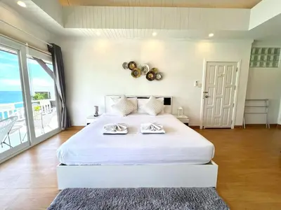 a bedroom with a large white bed and a balcony at Jaokhun Bayview Kamala, Phuket in Kamala Beach