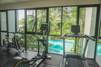 a gym with two exercise bikes and a swimming pool at Diamond Resort in Bang Tao Beach