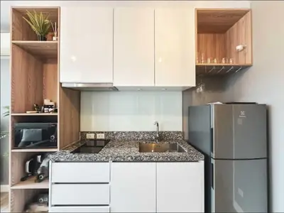 a kitchen with white cabinets and a stainless steel refrigerator at Diamond Resort in Bang Tao Beach