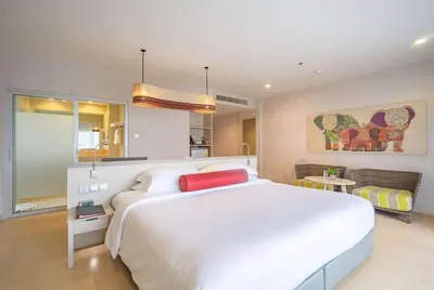 a bedroom with a large white bed with a red pillow at Ramada by Wyndham Phuket Deevana in Patong Beach
