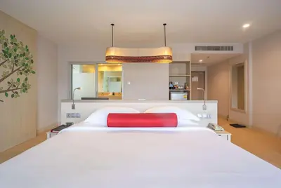 a large white bed with a red pillow on it at Ramada by Wyndham Phuket Deevana in Patong Beach