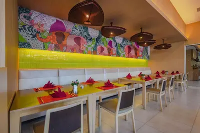 a restaurant with tables and chairs and a colorful wall at Ramada by Wyndham Phuket Deevana in Patong Beach