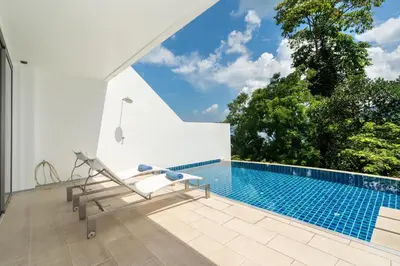 a swimming pool with a chair next to a house at Atika Villa 7 ocean view pool villa in Patong Beach