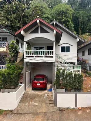 a red car parked in the garage of a house at Newly Renovated Sea View House in Karon Beach