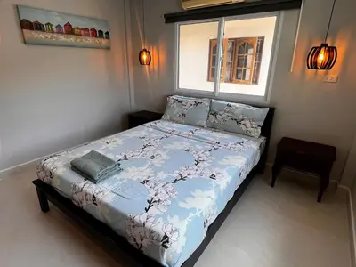 a bedroom with a bed with a blue comforter and a window at Newly Renovated Sea View House in Karon Beach