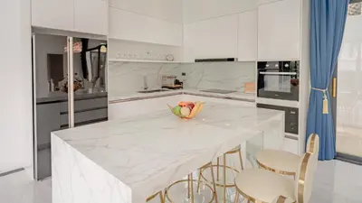 a white kitchen with a large marble table and chairs at Bang Tao Luxury Villa - Menara Hill in Ban Phak Chit