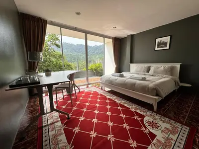 a bedroom with a bed and a table and a large window at Ananda Place in Ban Pa Khlok