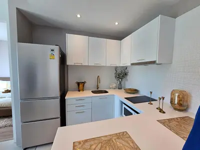 a kitchen with white cabinets and a refrigerator at The City Condo Near Central Fest Phuket, Pool view in Ban Sam Kong