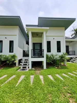 a house with a green lawn in front of it at Nua Tone Riverside Resort in Ban Thalat Choeng Thale