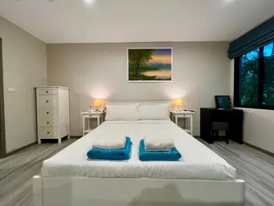 a bedroom with a large white bed with blue pillows on it at The Title NaiyangPhuket1 in Phuket