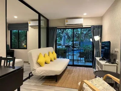 a living room with a white couch with yellow pillows at The Title NaiyangPhuket1 in Phuket