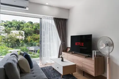 a living room with a grey couch and a tv at Karon Beach Hill View Appartment in Karon Beach