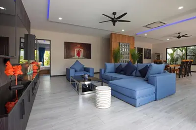 a living room with a blue couch and a table at Stylish 4 bdrs new brand pool villa at Rawai kokmakham 1 in Rawai Beach