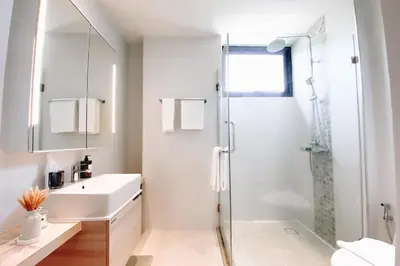 a white bathroom with a shower and a sink at Solara Stays Phuket in Bang Tao Beach