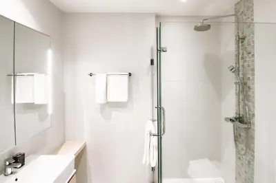 a white bathroom with a shower and a sink at Solara Stays Phuket in Bang Tao Beach