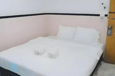 a white bed with white sheets and pillows at XX Mitr Inn - Phuket Old Town in Phuket Town