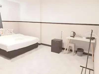a white room with a bed and a table at XX Mitr Inn - Phuket Old Town in Phuket Town